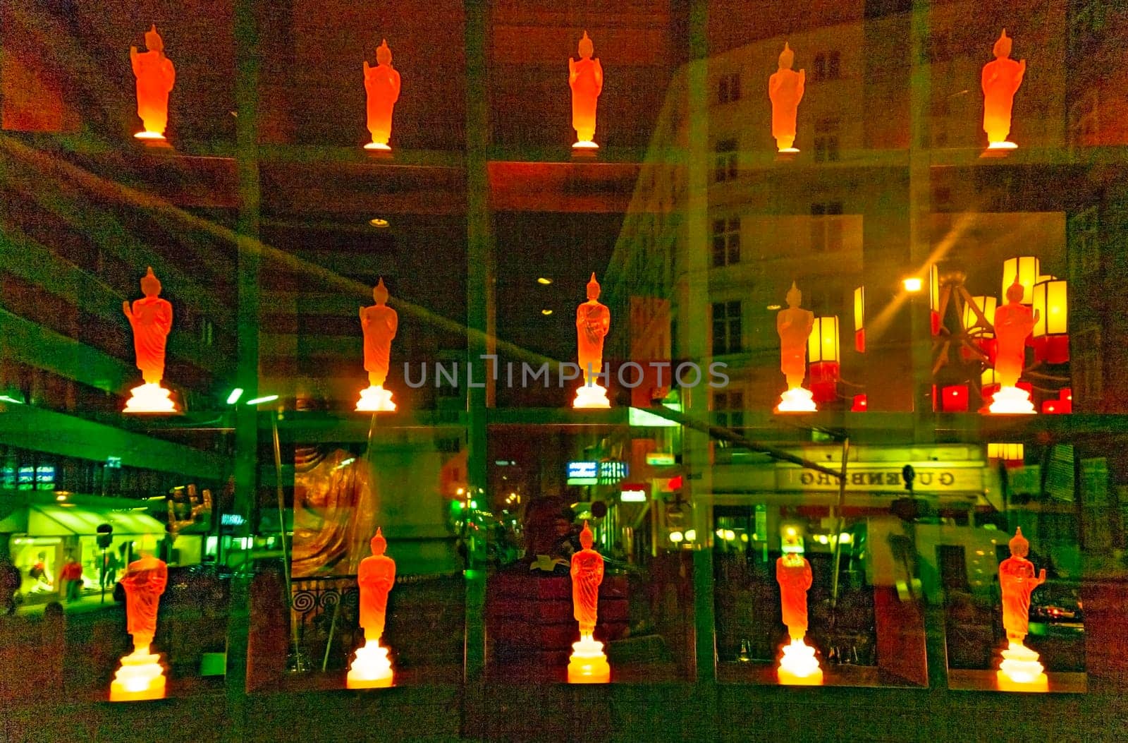 Vienna, Austria - December 5, 2009: colorful buddha statue in a shop with reflection of street light in glass window by night.