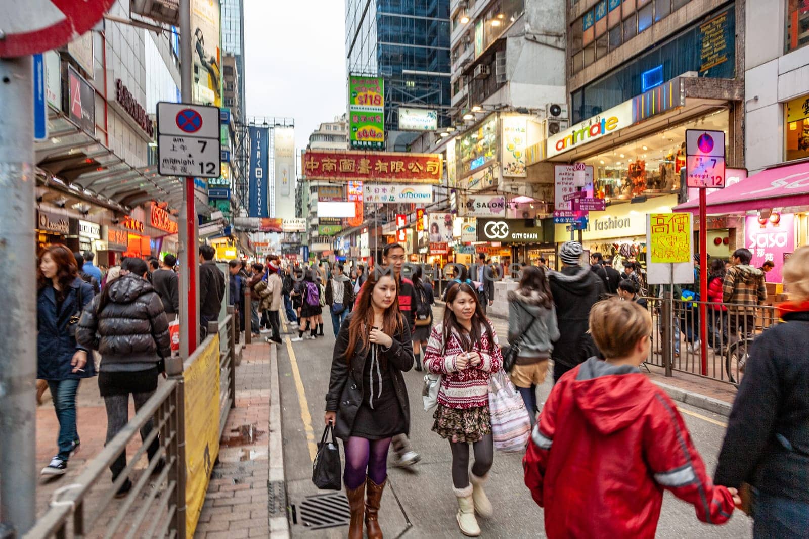 Hongkong, China - January 7, 2010: shopping street in late afternoon with illuminated shops and people hurry around in downtown Hongkong, Kowloon.