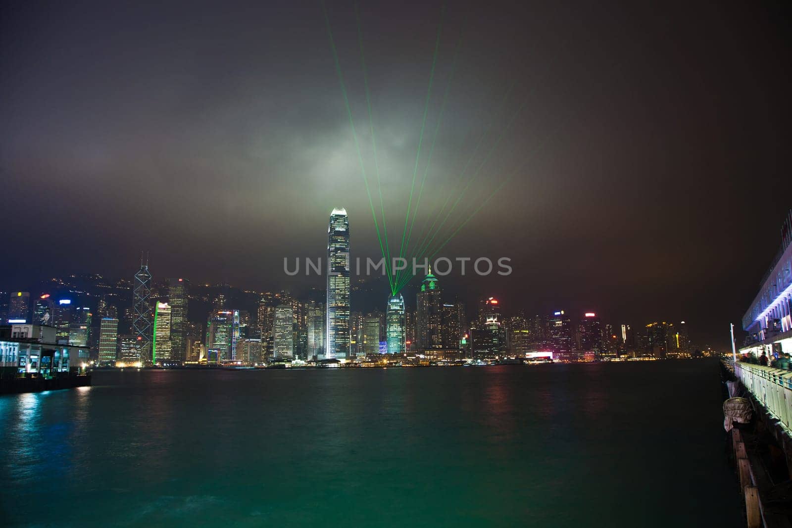 Kowloon, Hongkong - January 7, 2010: Hong Kong skyline at night with lights and skyscrapers over sea with laser beams