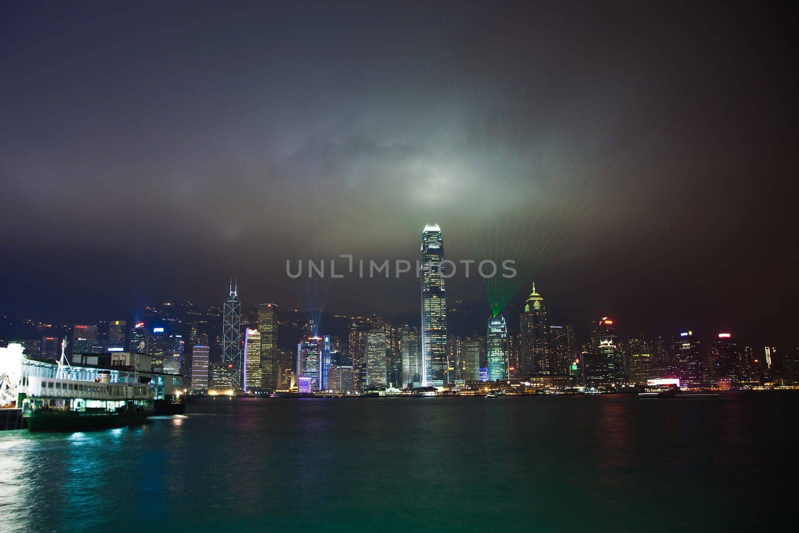 Kowloon, Hongkong - January 7, 2010: Hong Kong skyline at night with lights and skyscrapers over sea with laser beams