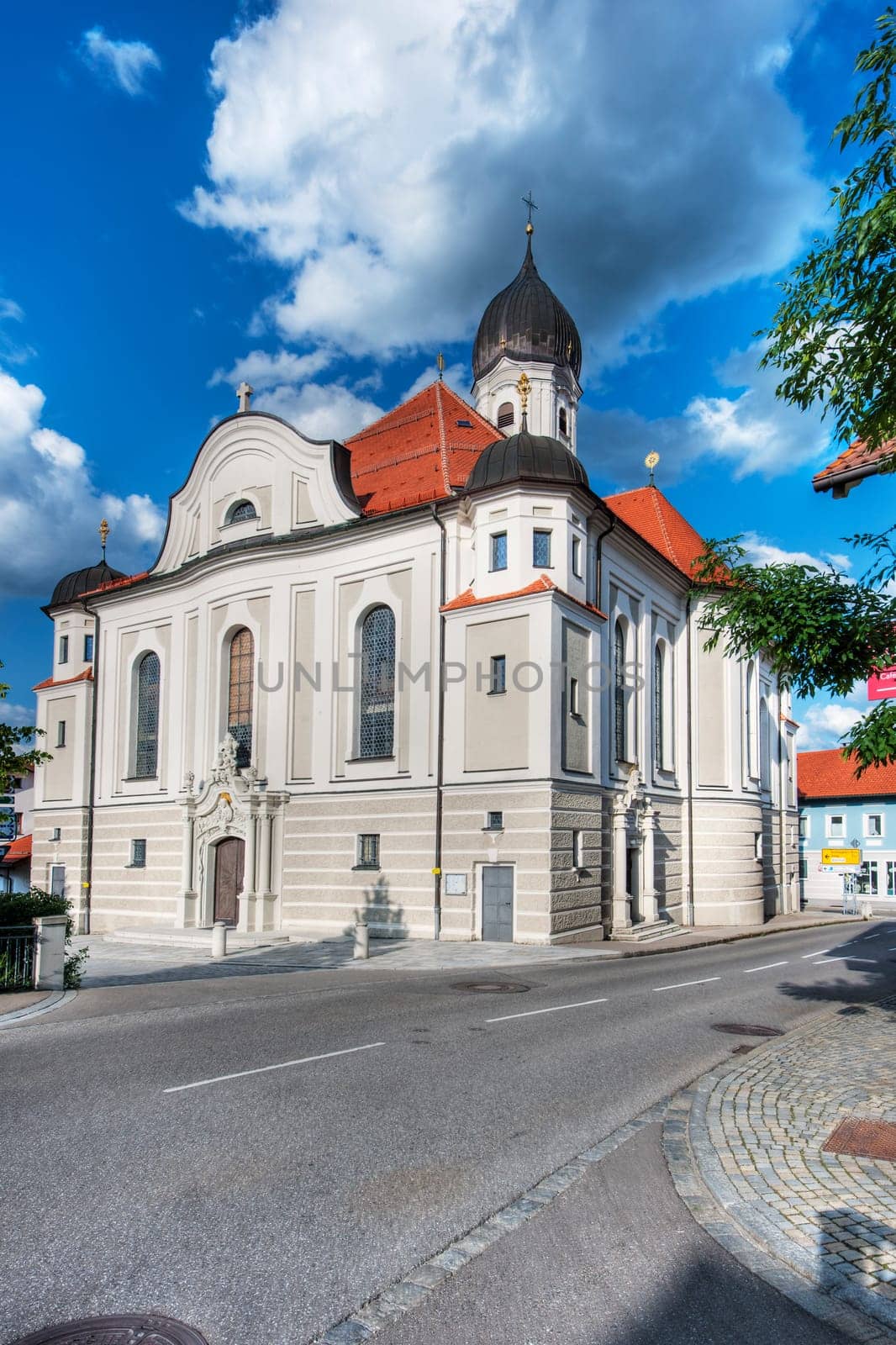Nesselwang, Germany - July 06, 2023: Wide angle corner view of the Saint Andreas Church in Nesselwang from the south-west against a blue sky with white clouds.
