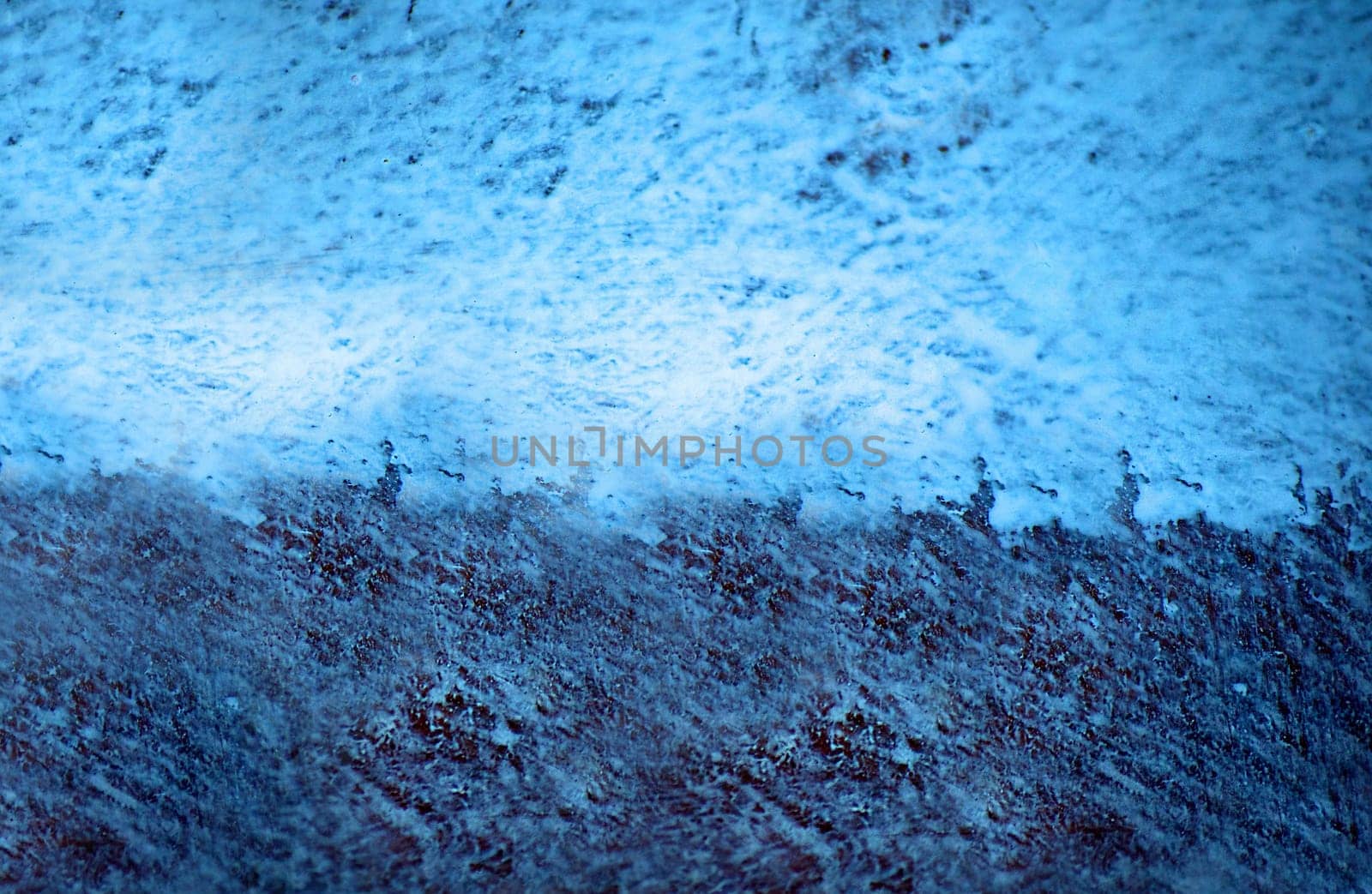 Half of the surface is irregularly colored in light blue and dark blue colors close-up view from above