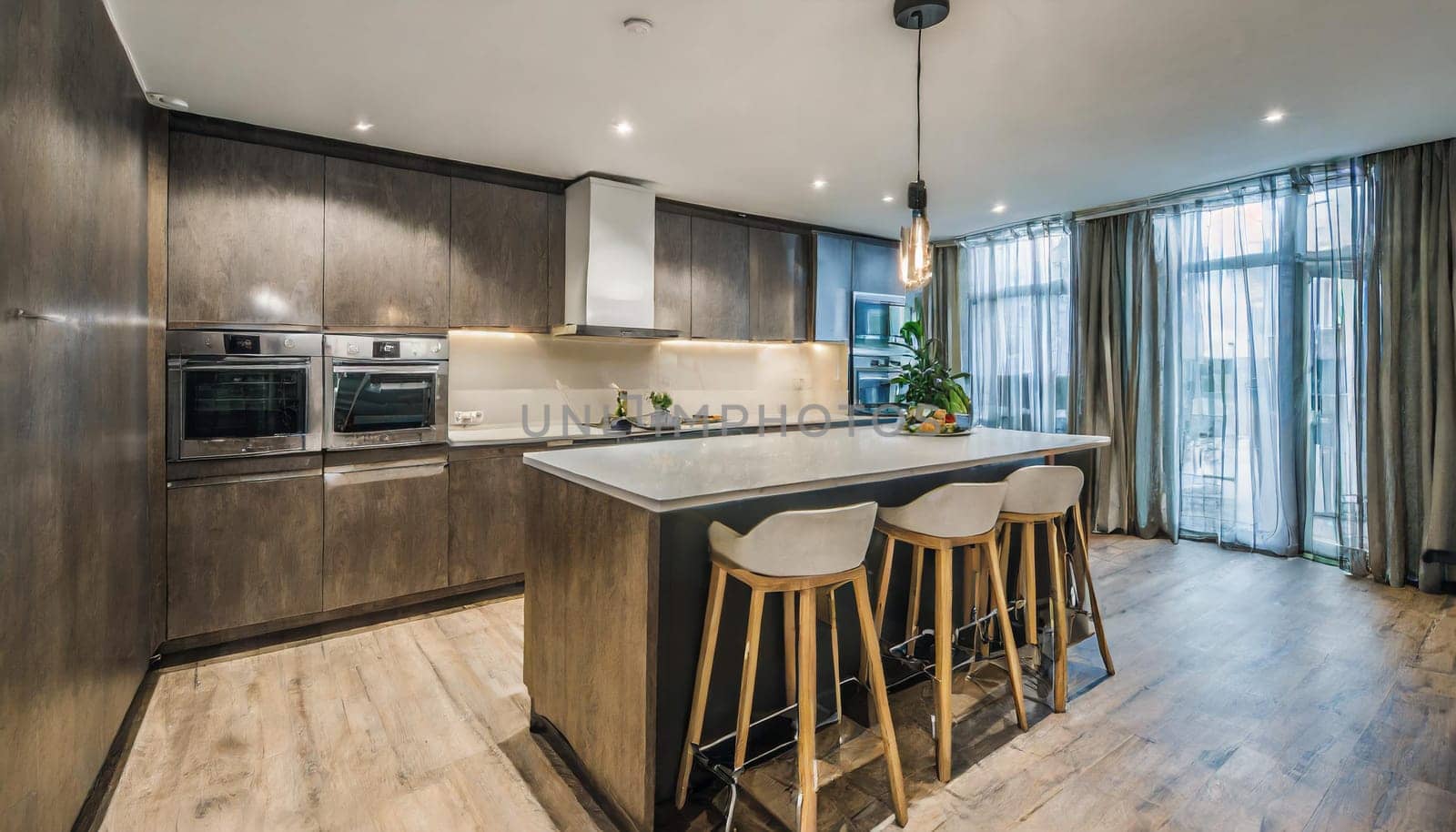 Cozy studio apartment with inviting interior featuring a comfortable brown sofa curtains and a cream colored kitchen with an island