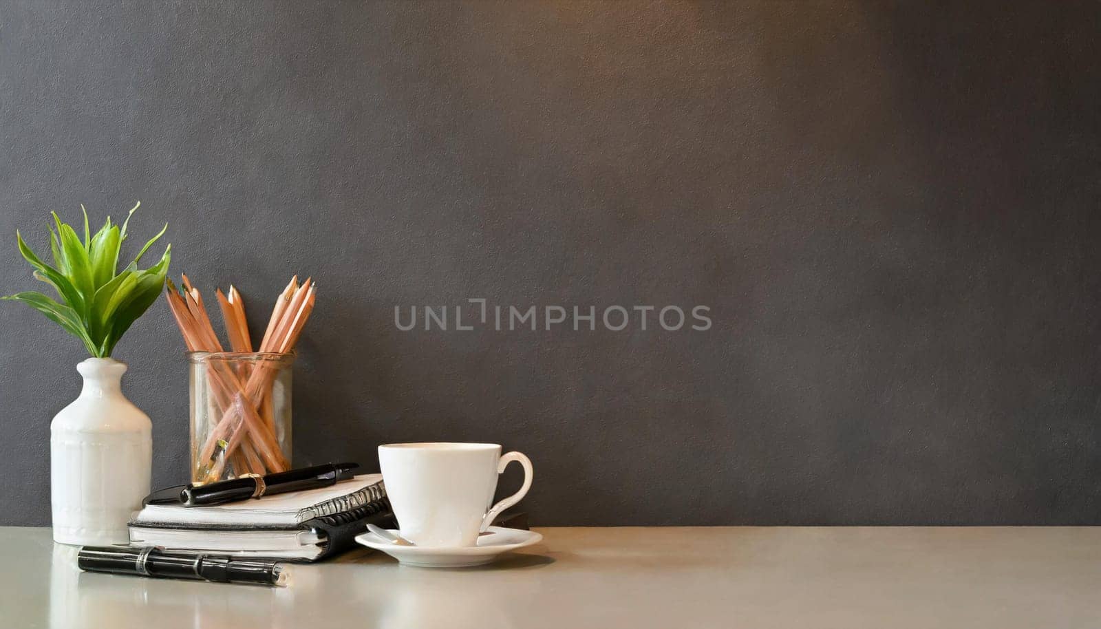 office table with copy space, stationery, vase, and lamp.