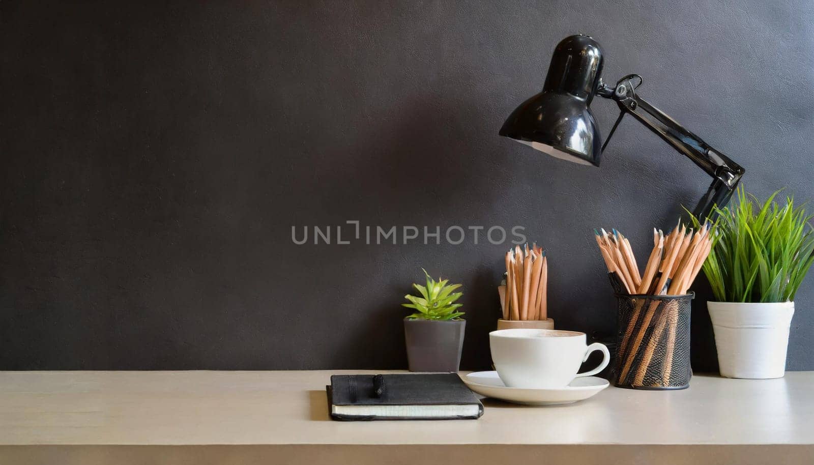 office table with copy space, stationery, vase, and lamp.