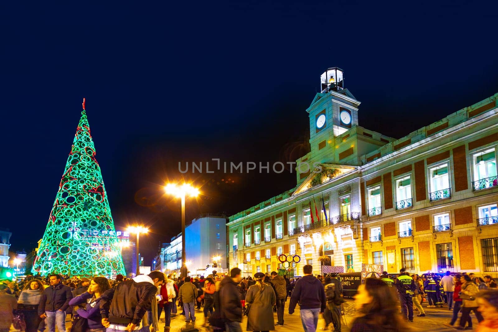 Madrid, Spain - December 22, 2010:  People have fun in Christmas time passing the famous illuminated christmas tree at puerta del sol in Madrid, Spain.