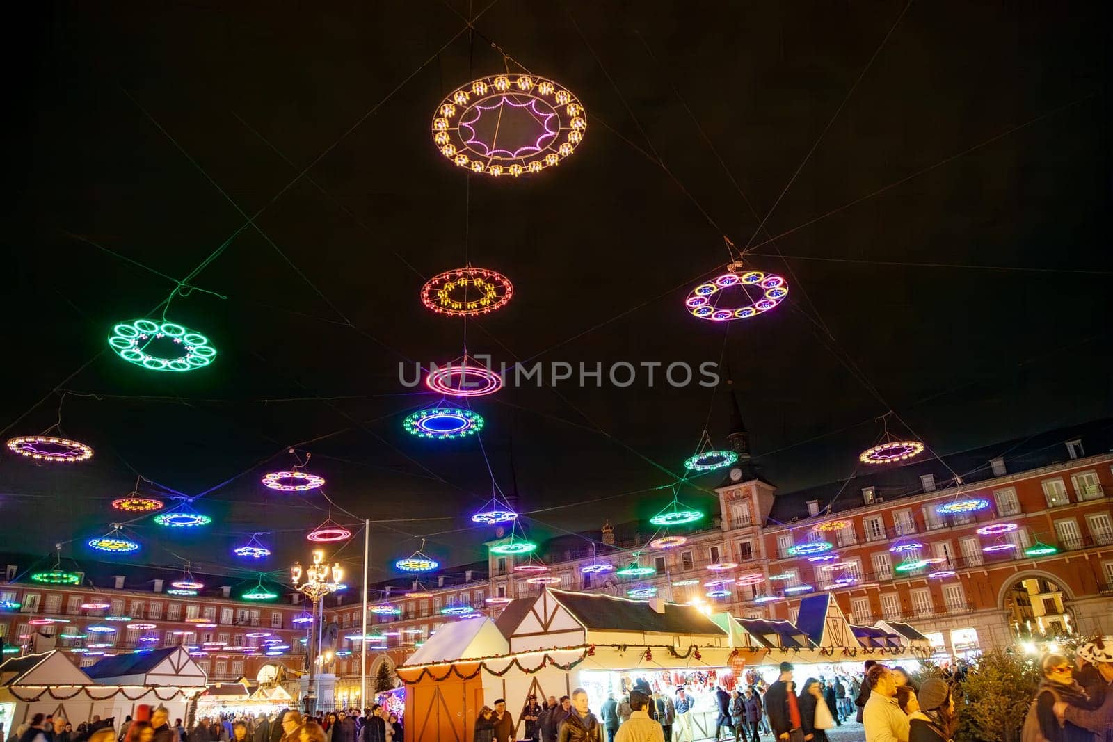 Madrid, Spain - December 22, 2010:  People buy Christmas presents in market stalls by night on Plaza Mayor, the most famous Christmas market in Madrid, Spain.