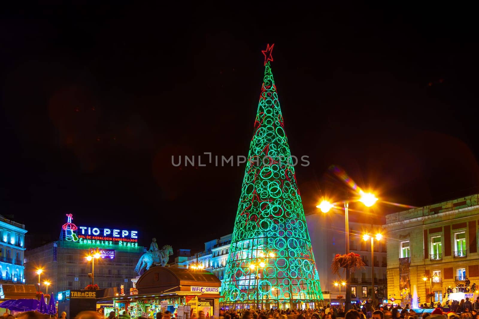 Madrid, Spain - December 22, 2010:  People have fun in Christmas time passing the famous illuminated christmas tree at puerta del sol in Madrid, Spain.