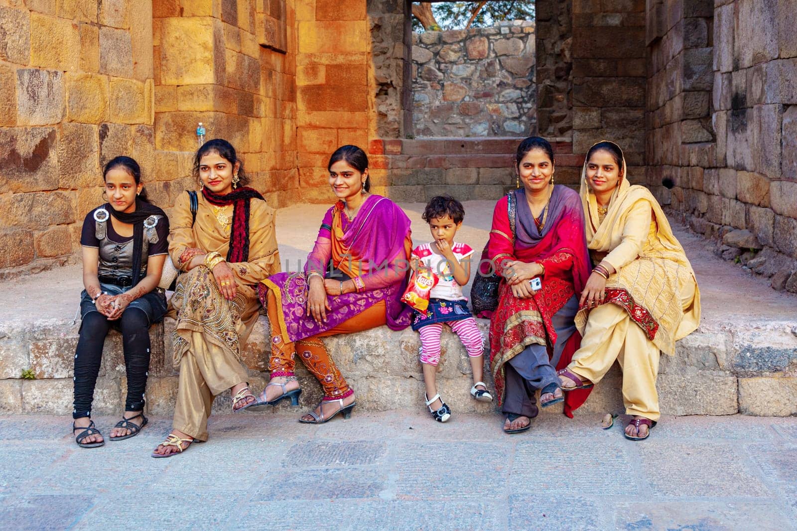 New Delhi, India - November 13, 2011:  indian tourists in colorful festival dress visit the minaret Qutub Minar in New Delhi, the worlds tallest brick minaret with 72 meters.