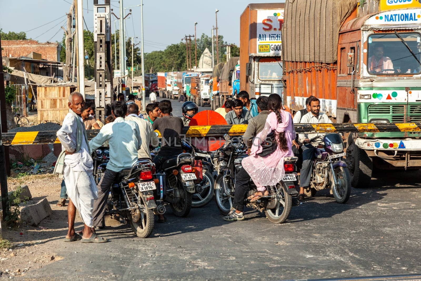 Fathepur Sikri, India - November 16, 2011: people at a train crossing wait for the passing train to continue travel.