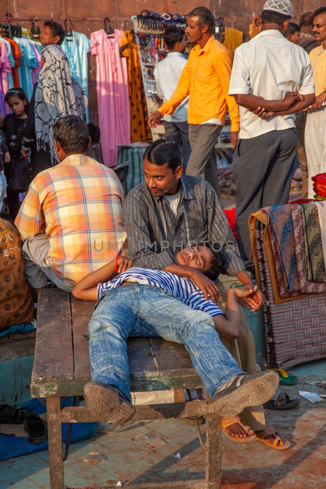 New Delhi, India - November 17, 2011: people at Meena Bazaar in Chandni Chowk area selling goods at the old open air market in India, a hawker is sleeping on a wooden chart.