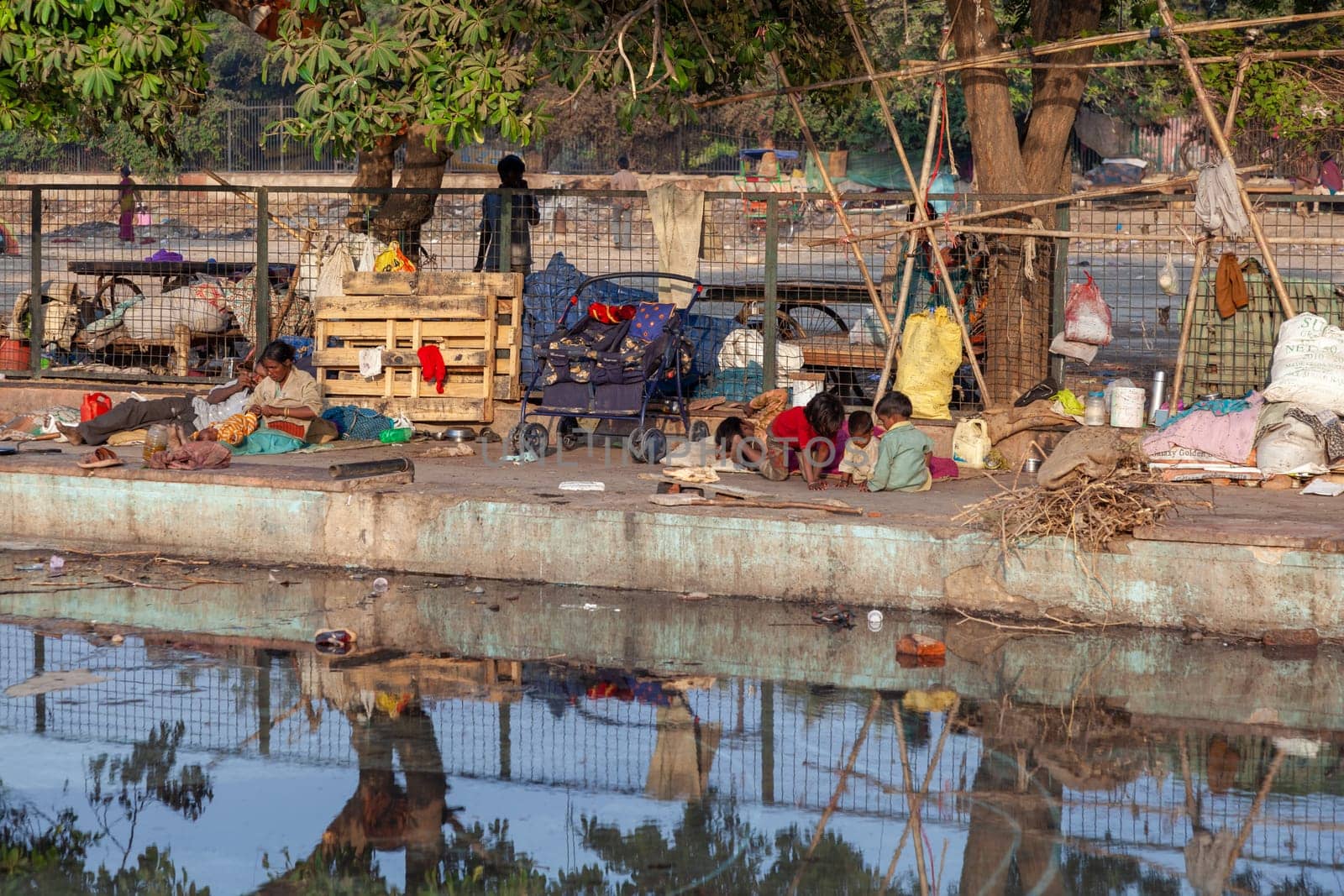 Delhi, India - November 17, 2011: poor homeless families live at the Meena Bazaar in area Chandni Chowk in New Delhi, India at a dirty water basin.