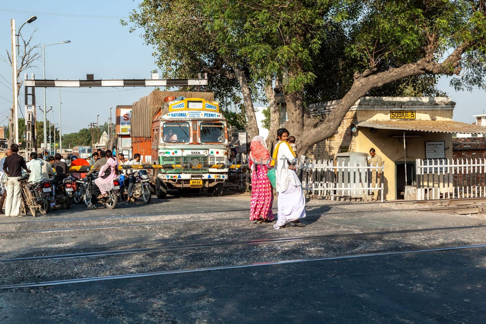 Fathepur Sikri, India - November 16, 2011: people at a train crossing wait for the passing train to continue travel.