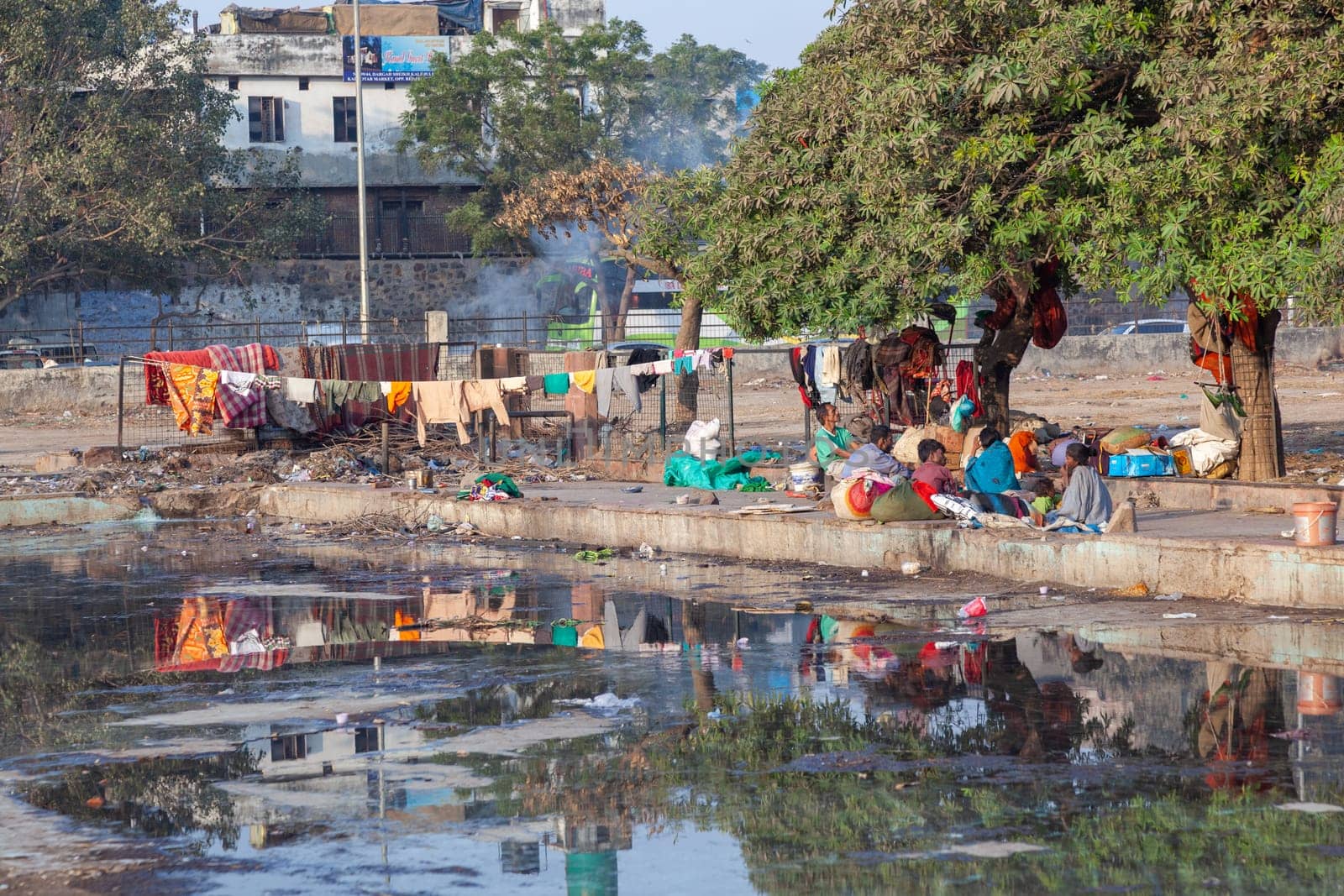 Delhi, India - November 17, 2011: poor homeless families live at the Meena Bazaar in area Chandni Chowk in New Delhi, India at a dirty water basin.
