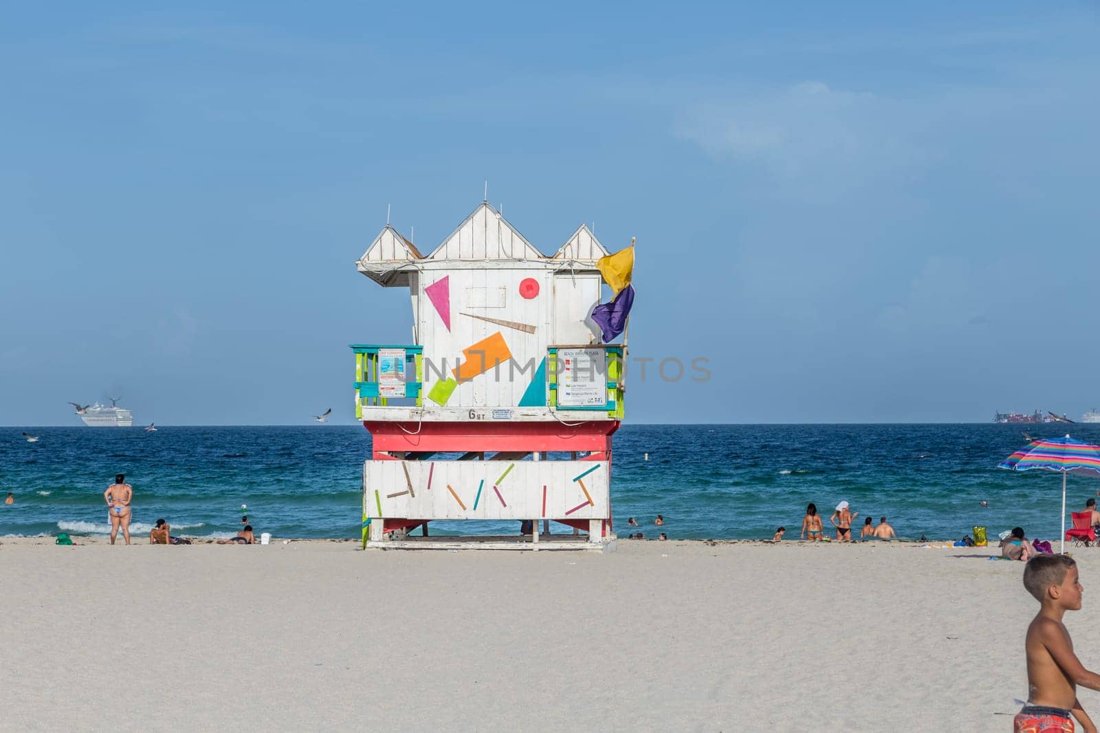 Miami, USA - August 18, 2014: People at the sea side in Miami with lifeguard tower, USA. Miami Beach is a popular destination among tourists, spiking during the winter time.