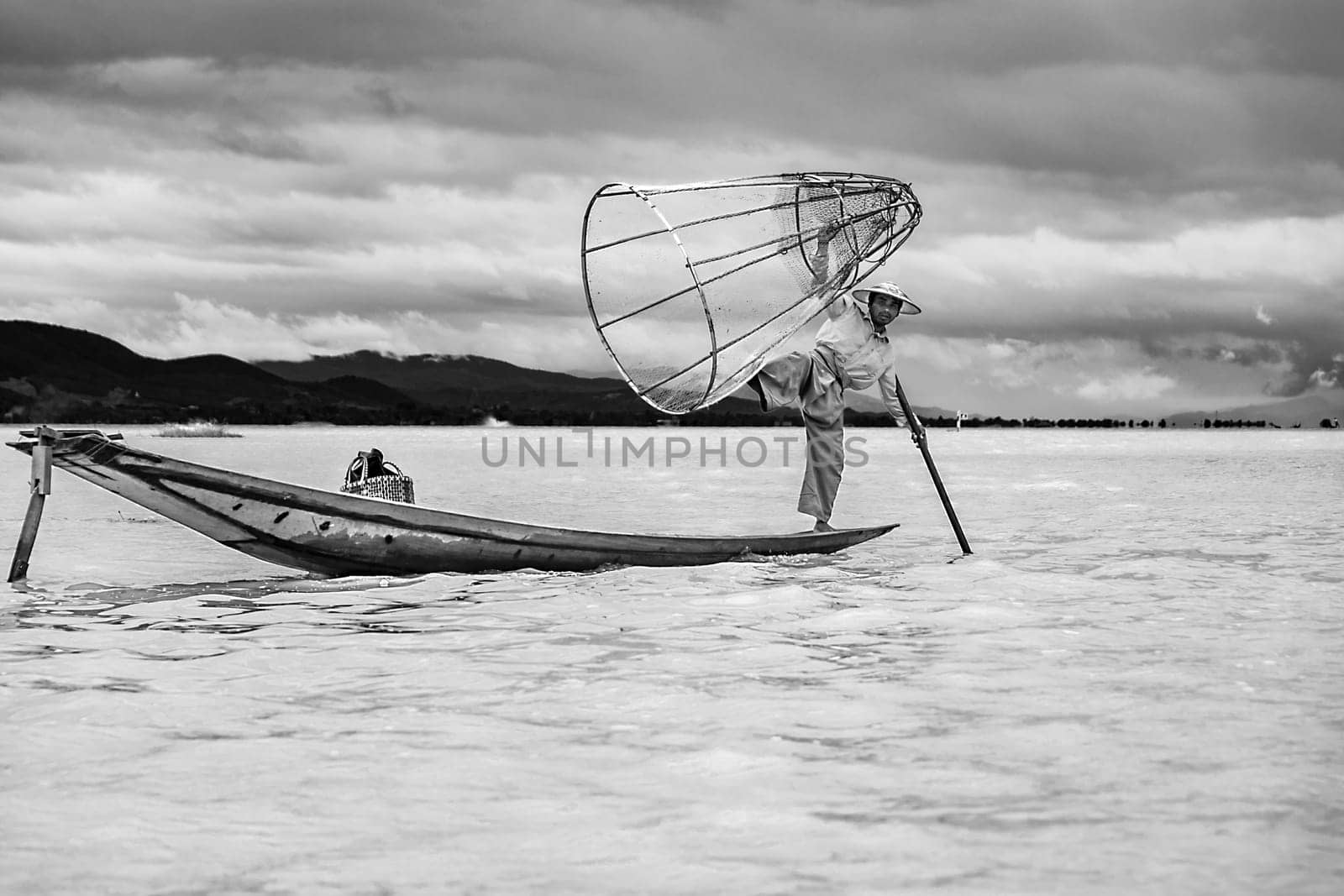 Heho, Myanmar - AUG 15, 2015 : Intha fisherman fishing  in his typical canoe with fishing net. The fishing net is handmade by the fisher.