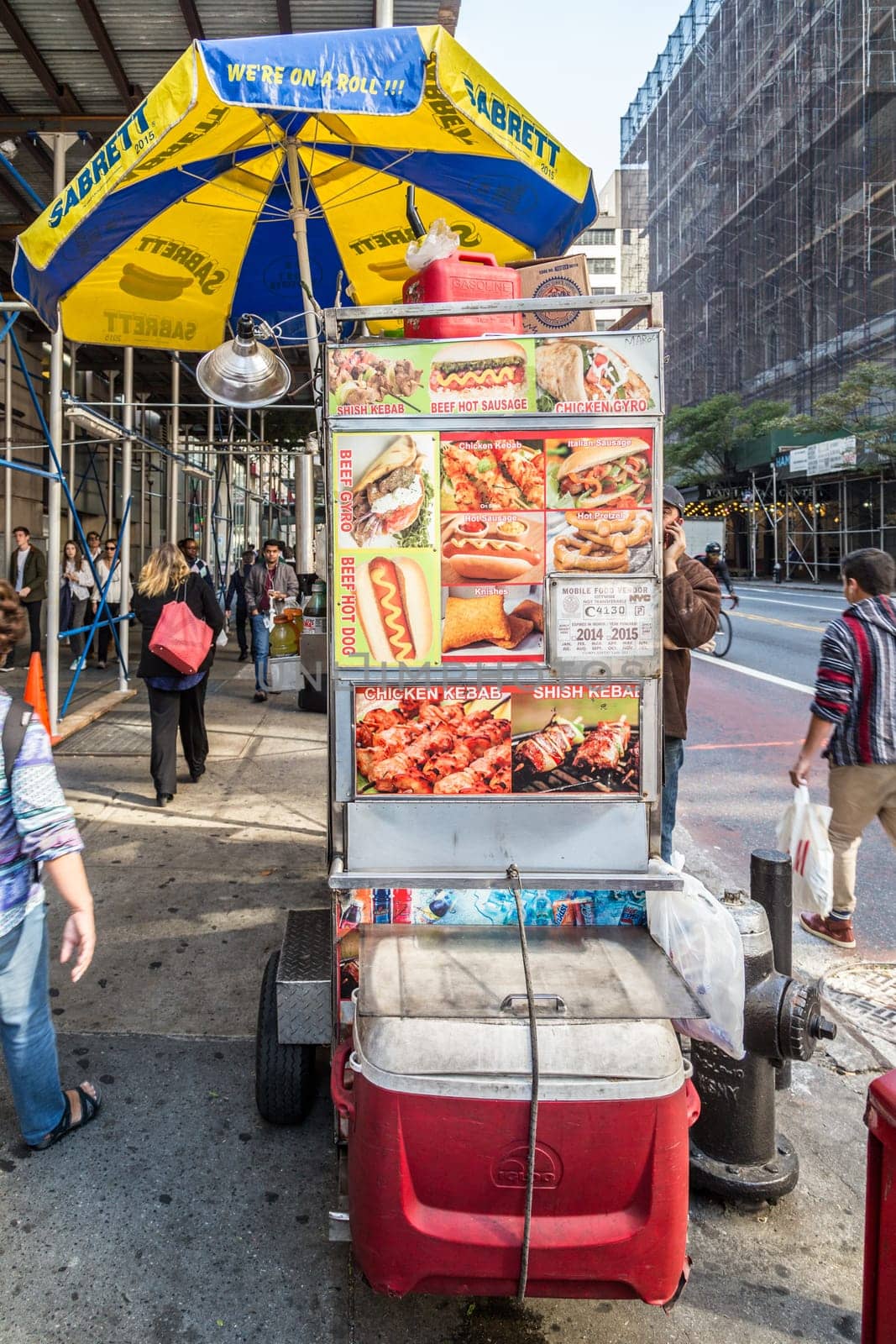 New York, USA - October 21, 2015: street view with mobile food vendor stall downtown New York. The vendor offers different kind of grilled or cooked meat.