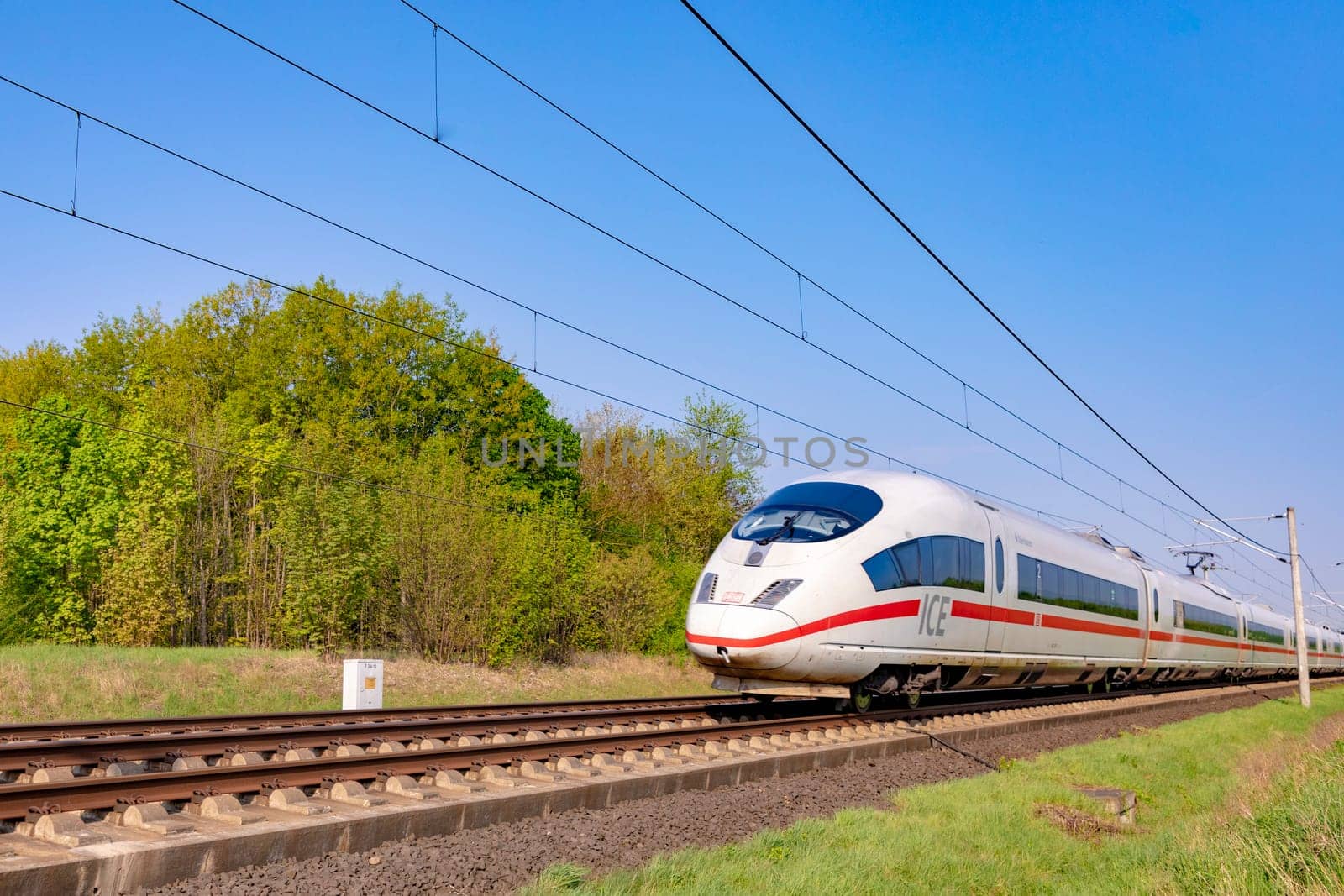 Raunheim, Germany - April 21, 2018: german high speed train Intercity Express (ICE) train of Deutsche Bahn passes rural landscape near Raunheim. ICE 3 class train is manufactured by Siemens.
