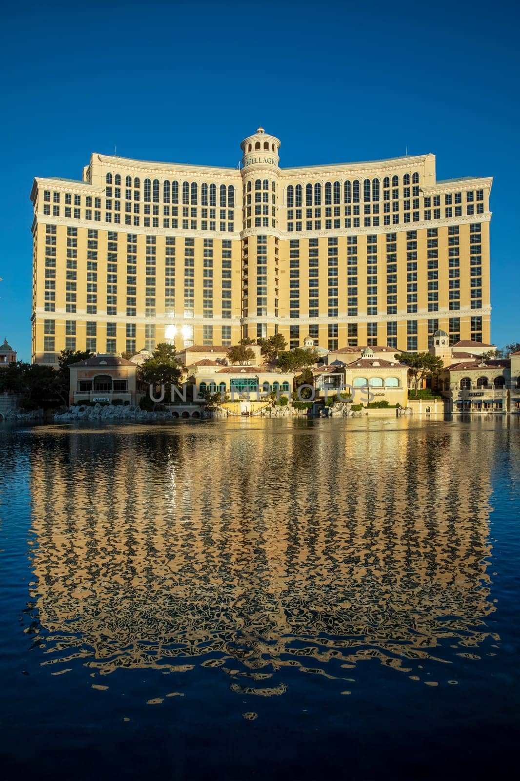 Las Vegas, USA - May 25, 2022: people pose at scenic historic famous Las Vegas welcome sign. view to Bellagio hotel with reflection in the lake in early morning light, Las Vegas, USA.