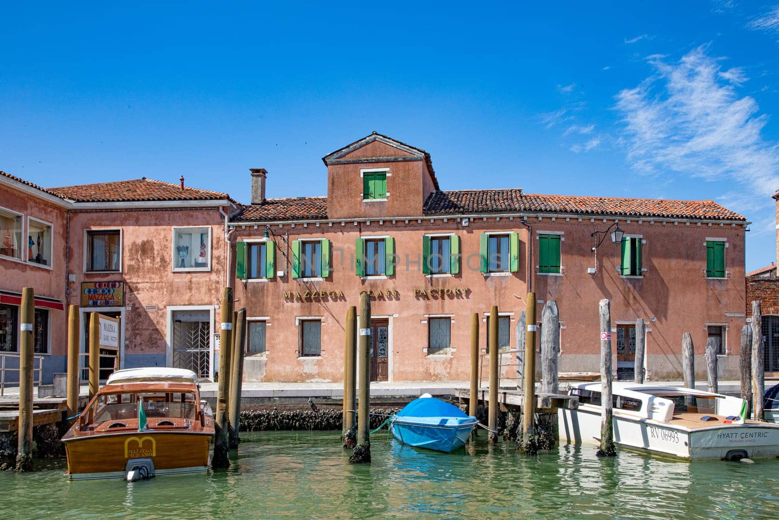 Murano, Italy - July 1, 2021: view to canal in Murano with facade of old traditional glass factory.