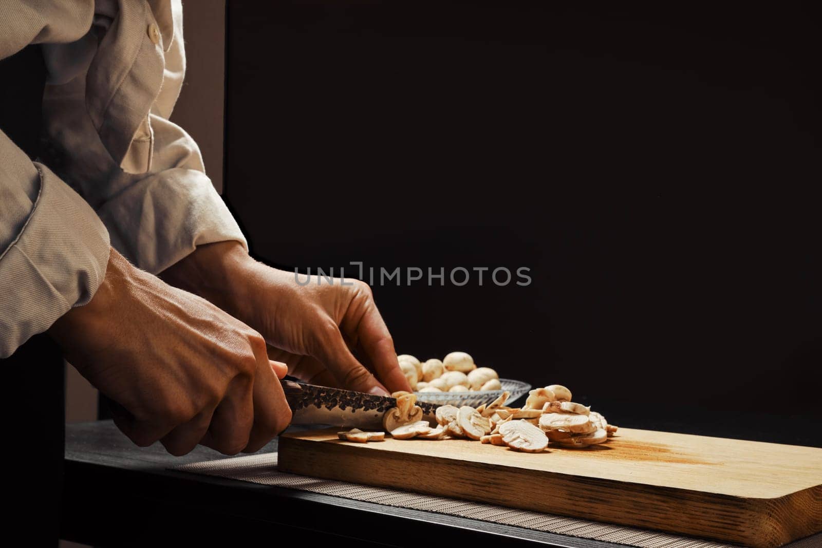 Hands of a woman cutting champignon mushrooms into thin slices