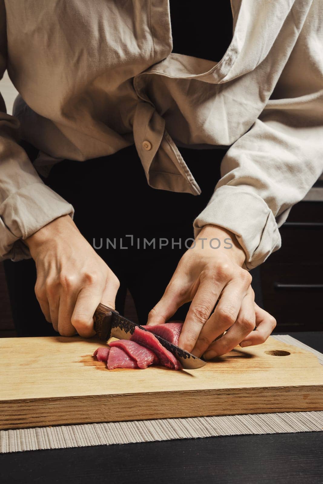 Close-up of woman's hands thinly slicing raw beef meat for Korean barbecue
