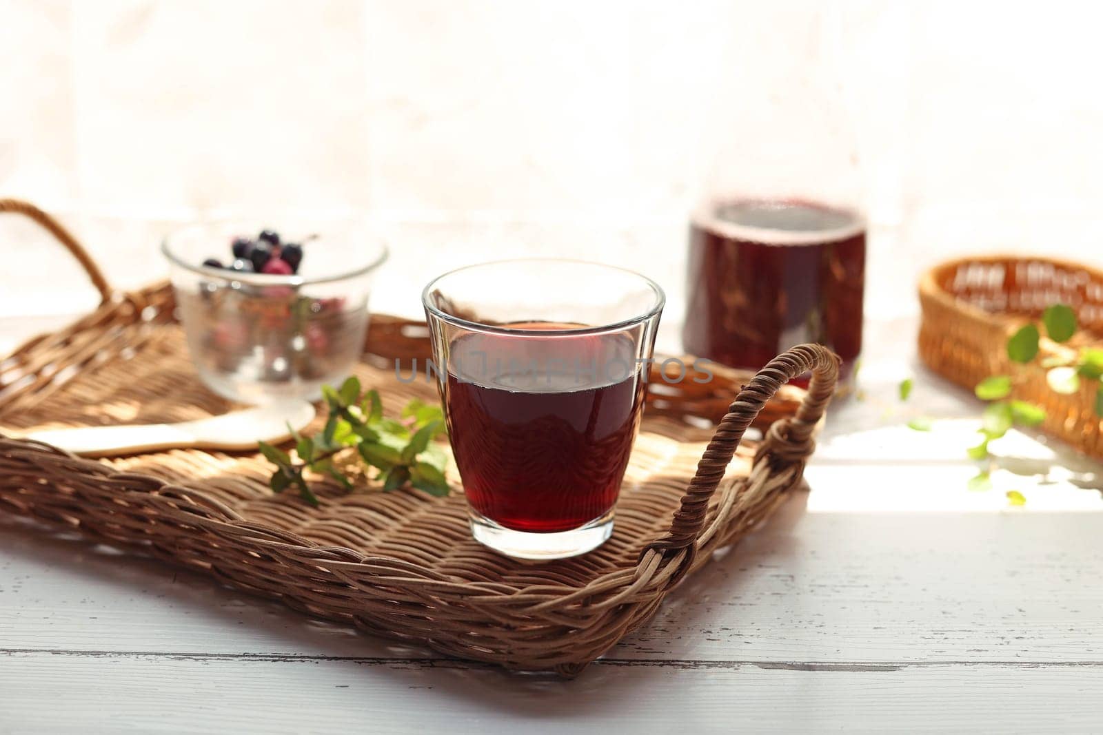 Grape juice poured into a glass on a rattan tray