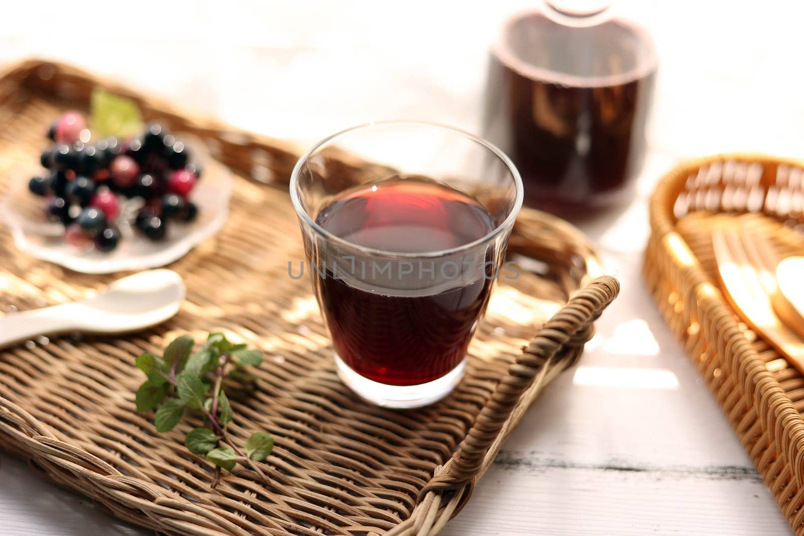 Grape juice poured into a glass on a rattan tray