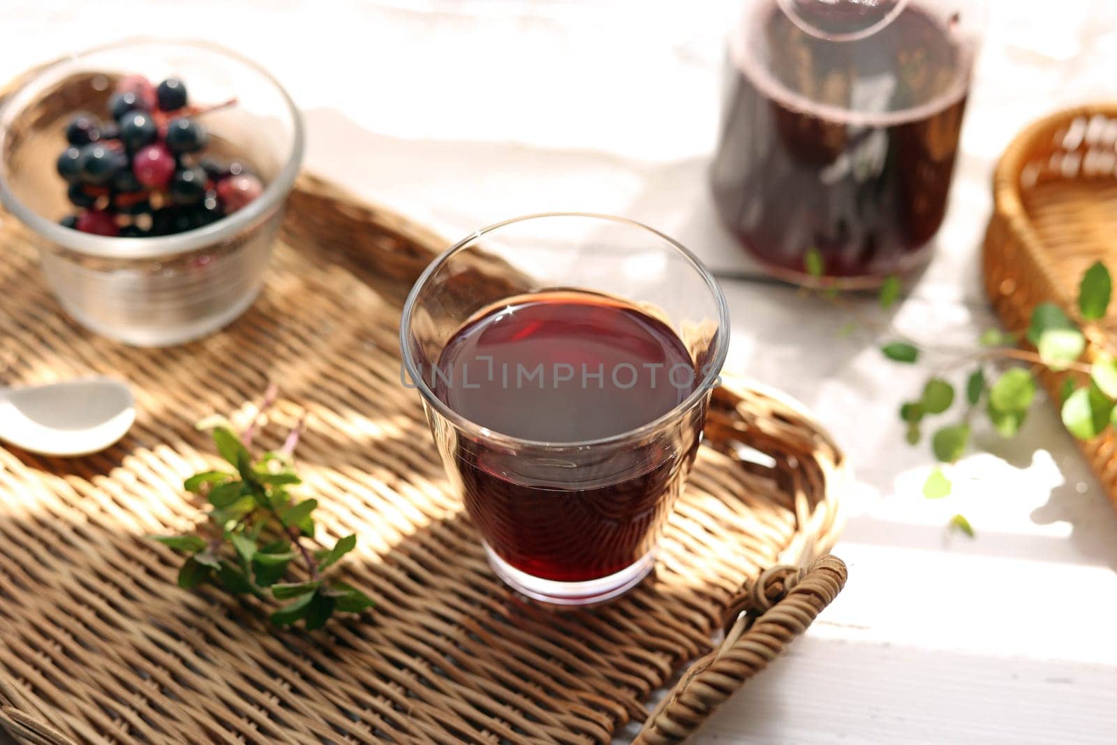 Grape juice poured into a glass on a rattan tray