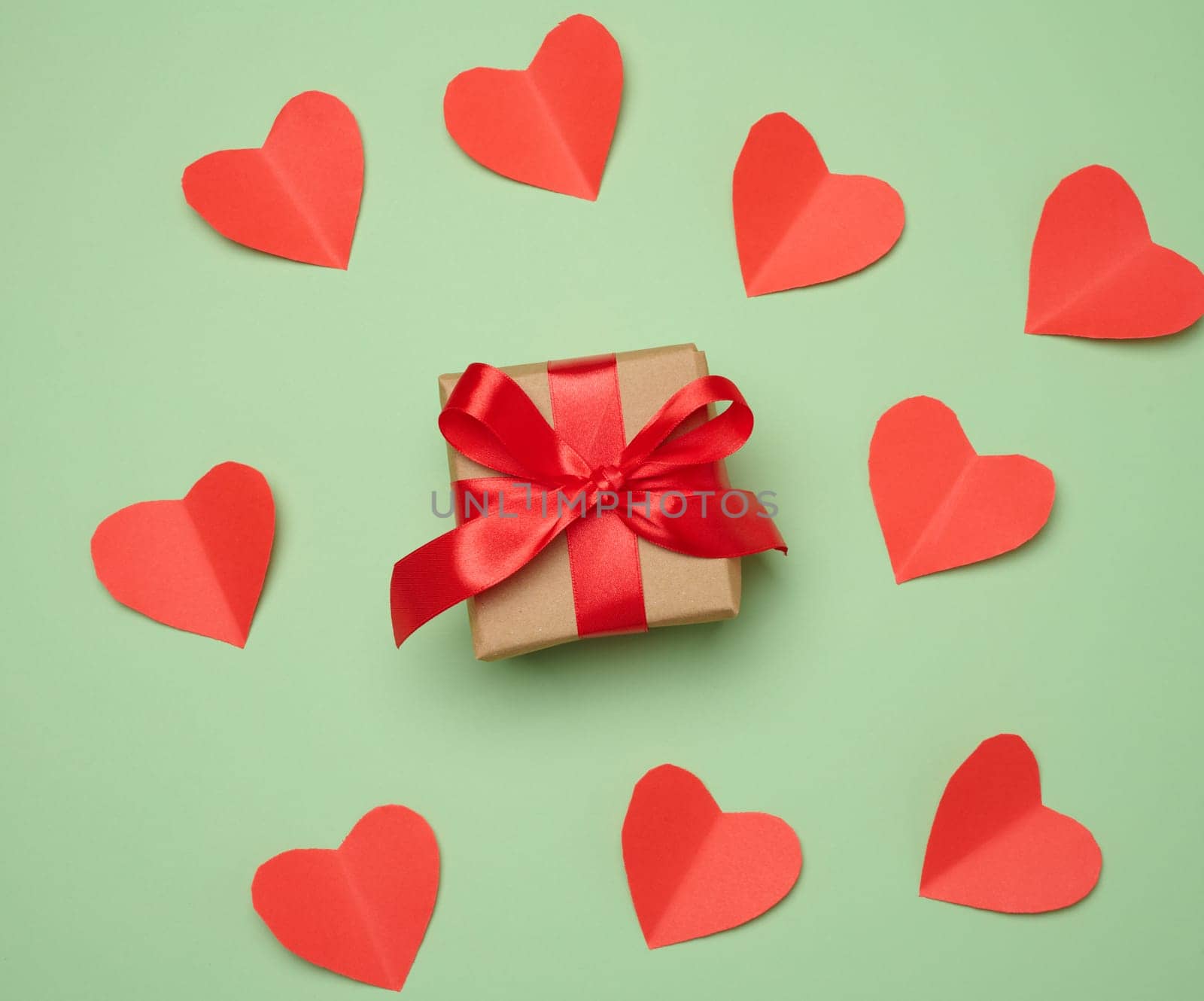 Gift box with red satin ribbon and bow on a green background.Holiday background, top view