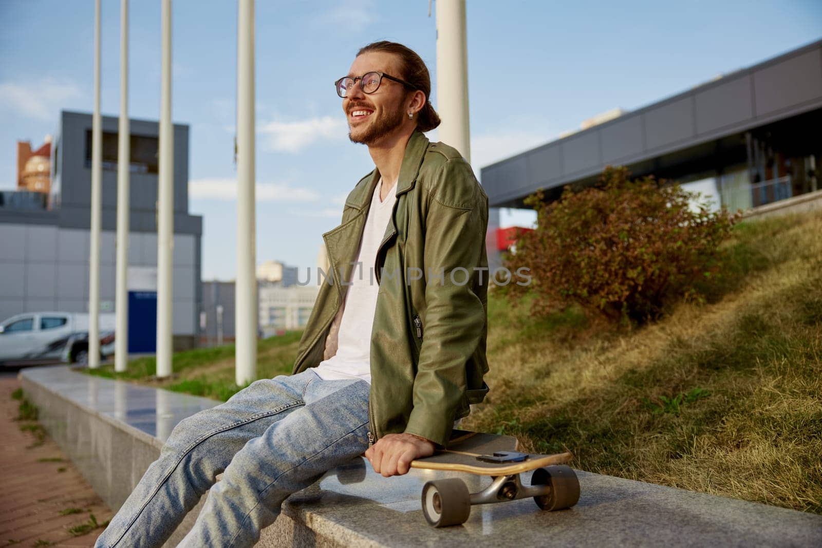 Young hipster sporty man with skateboard rest after training race in skate board park. Summer outdoor recreation time for active young people