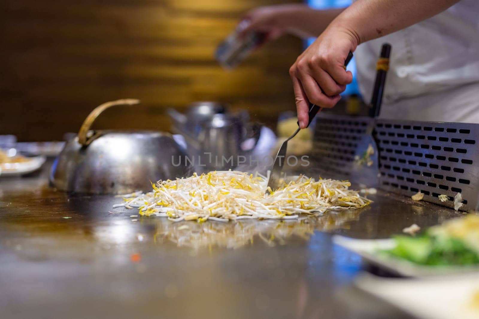 Teppanyaki chef preparing food on hot metal plate