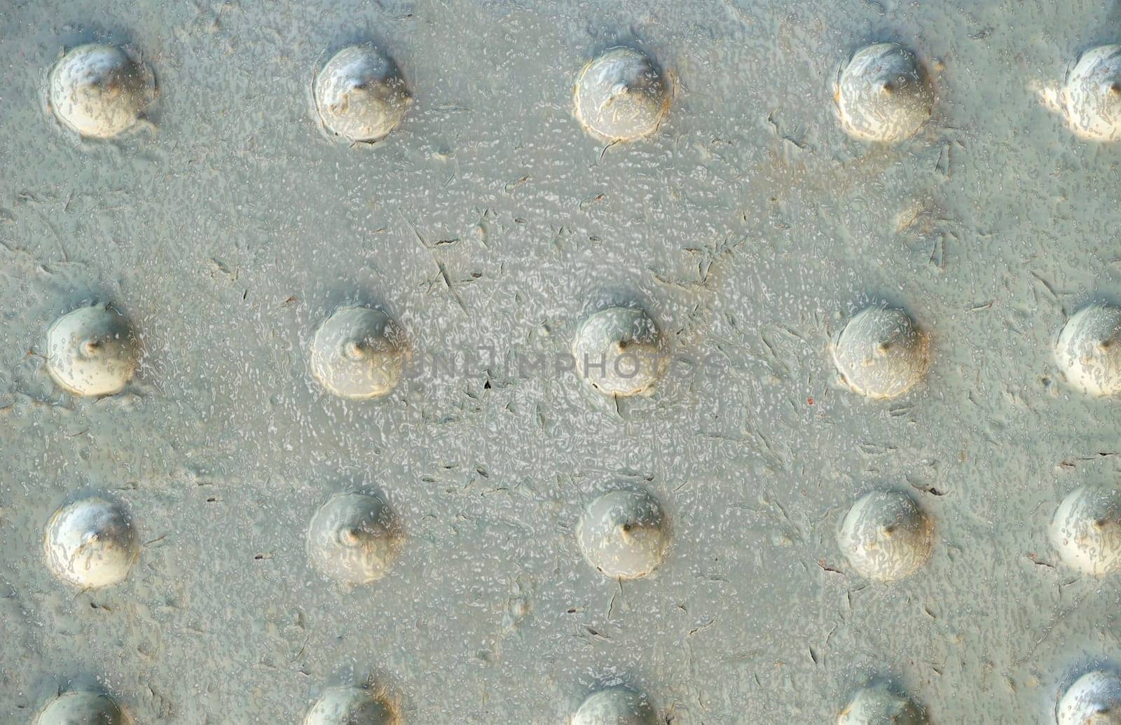 Grey glossy metal old surface with peeling paint and decorative bumps on the surface