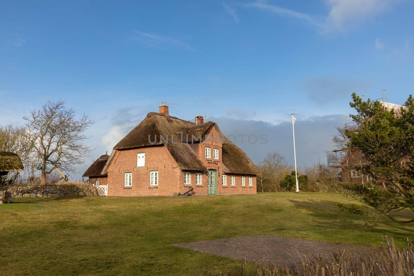List, Germany - February 17, 2021: typical red brick Frisian house with thatched roof on Sylt island in List village, Germany.