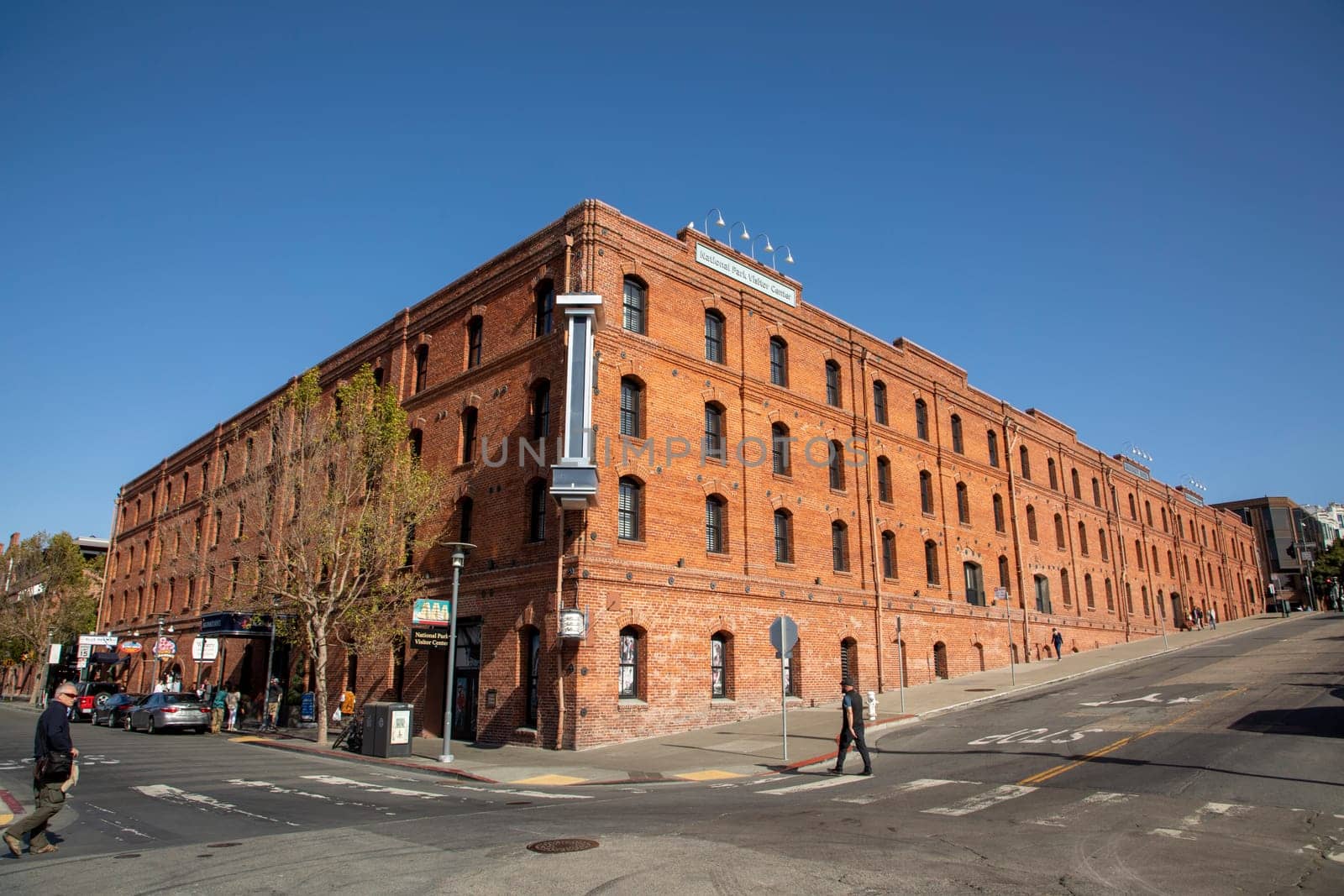 San Francisco, USA - May 17, 2022:  people enjoy walk alomg Jefferson street with old brick building belonging to San Francisco National maritime museum in early morning.