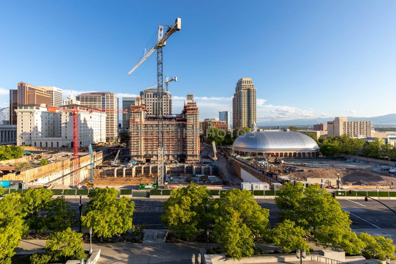 Salt Lake City, USA - May 28, 2022: view to Salt Lake Tabernacle (Church of Jesus Christ of Latter-day Saints) and the old temple under construction with downtown skyline of Salt Lake city.