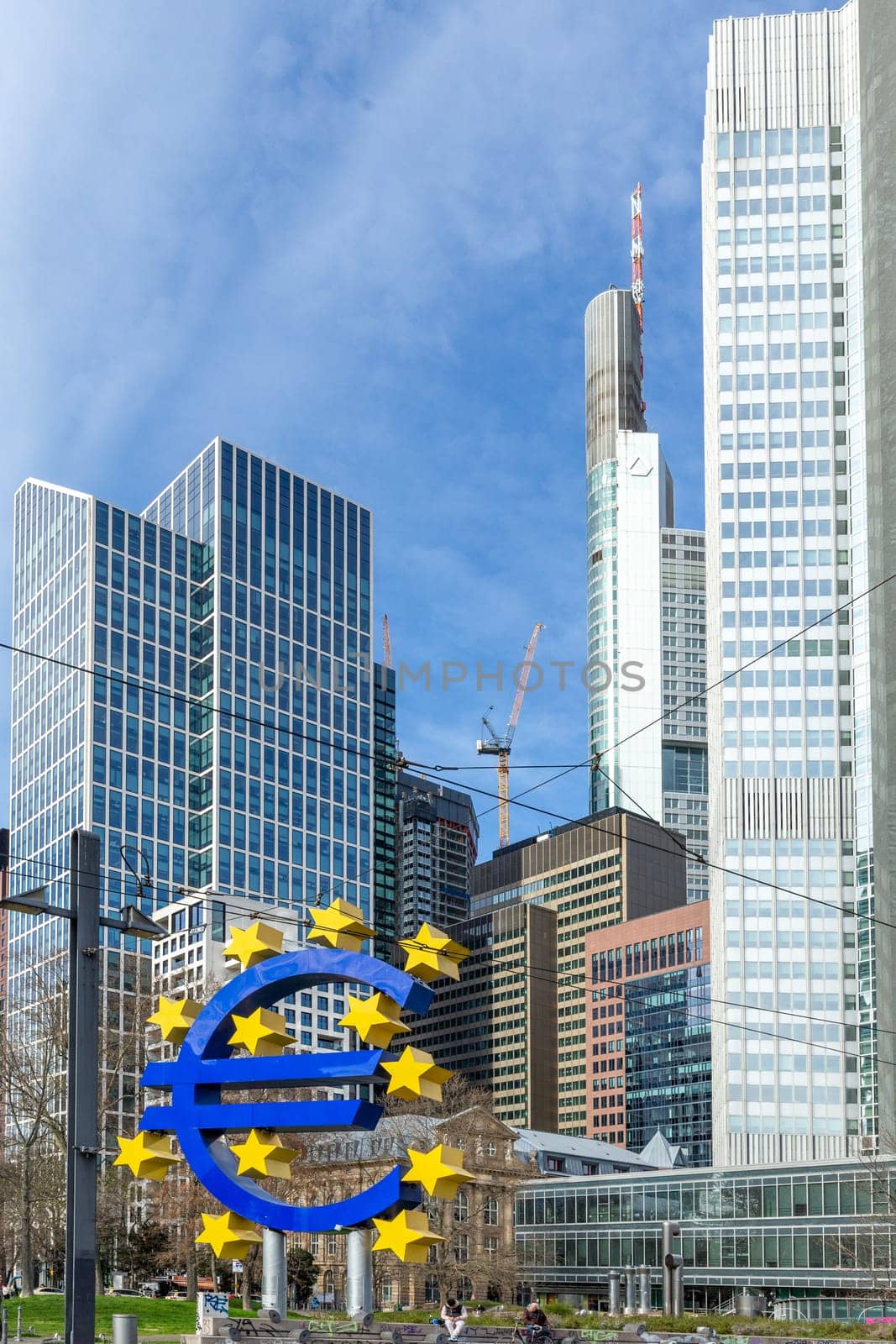 Frankfurt, Germany - March 28, 2023: the Euro sign in Frankfurt in front of skyscraper and the former european central bank building.