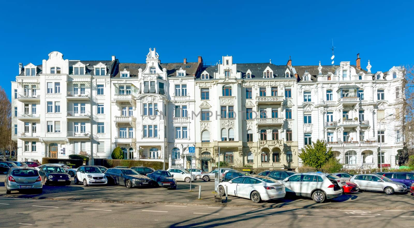 Wiesbaden, Germany - February 27, 2023:  facade of old historic house from the 18th century with balconies and a parking lot in front.