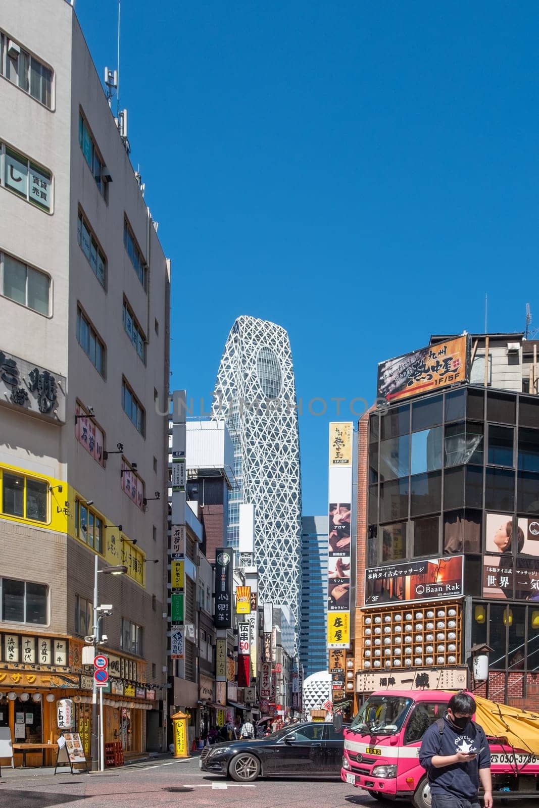 Tokyo, Japan - March 19, 2023: Street view of Nishi Shinjuku Shopping street whith several Japanese Restaurants on the sides. Mode Gakuen Cocoon Tower is at the background.