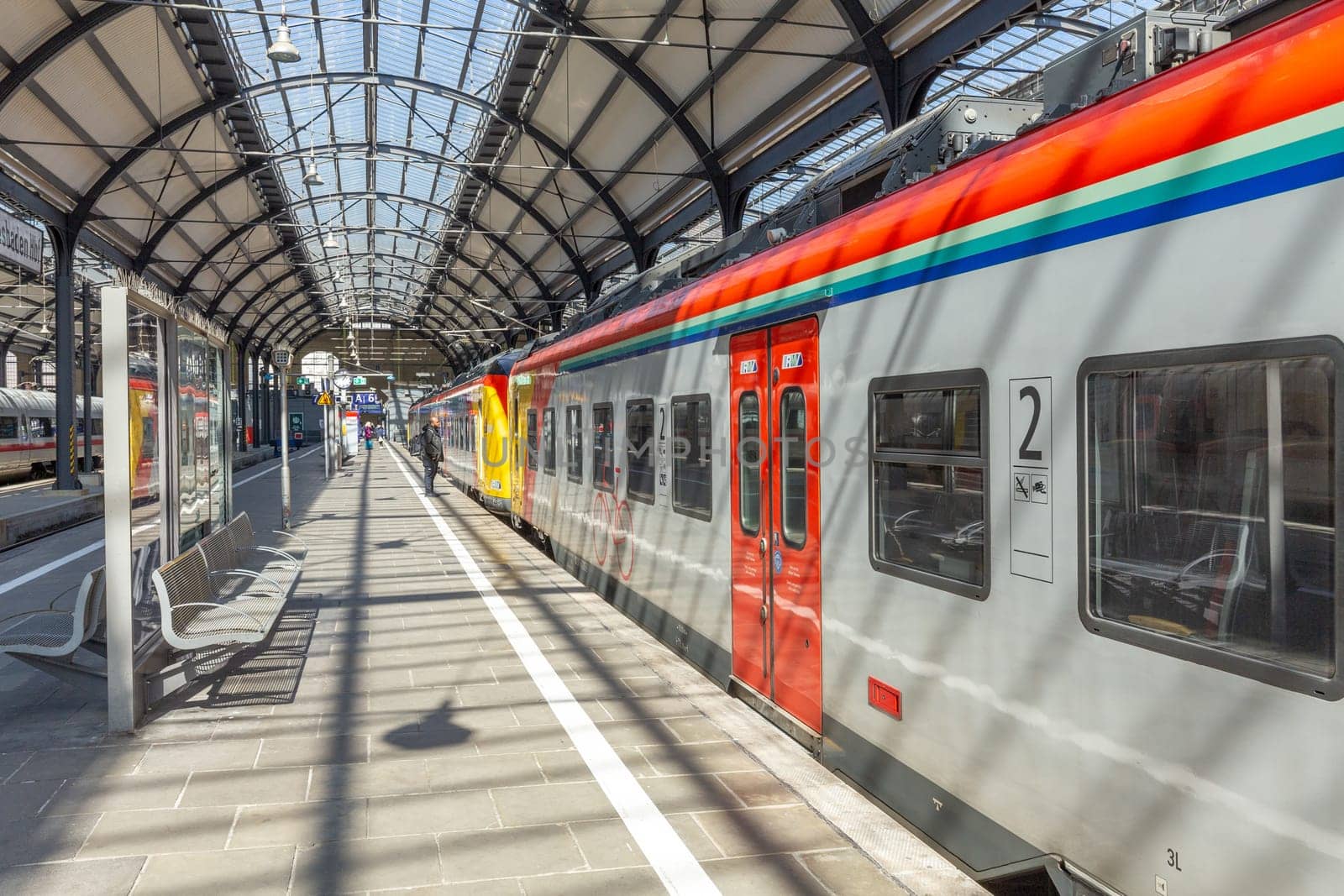 Wiesbaden, Germany - April 4, 2023:  people wait in the train station for departure in classicistic train station in Wiesbaden, the smaller copy of Frankfurt Train station.