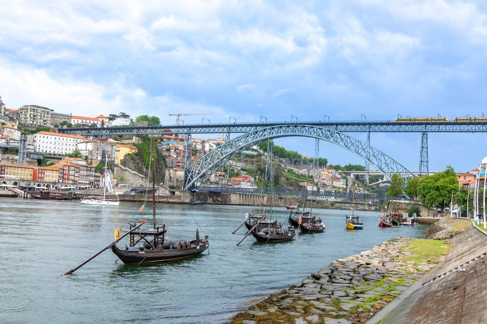 Porto, Portugal - May 3, 2023: old vinery ships at river Duoro with skyline of Porto in background and bridge ponte luis I in Gaia, Porto, Portugal.