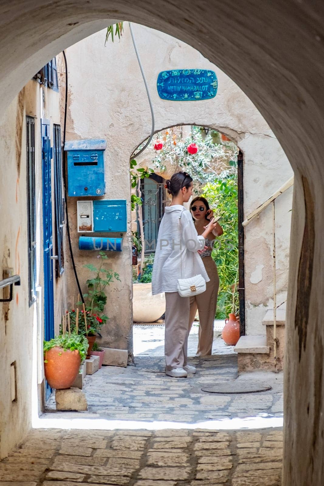 Tel Aviv, Israel - May 18, 2023: tourists enjoy walking at th old town of Tel Aviv with pittoresque old small arches, houses and courtyards.