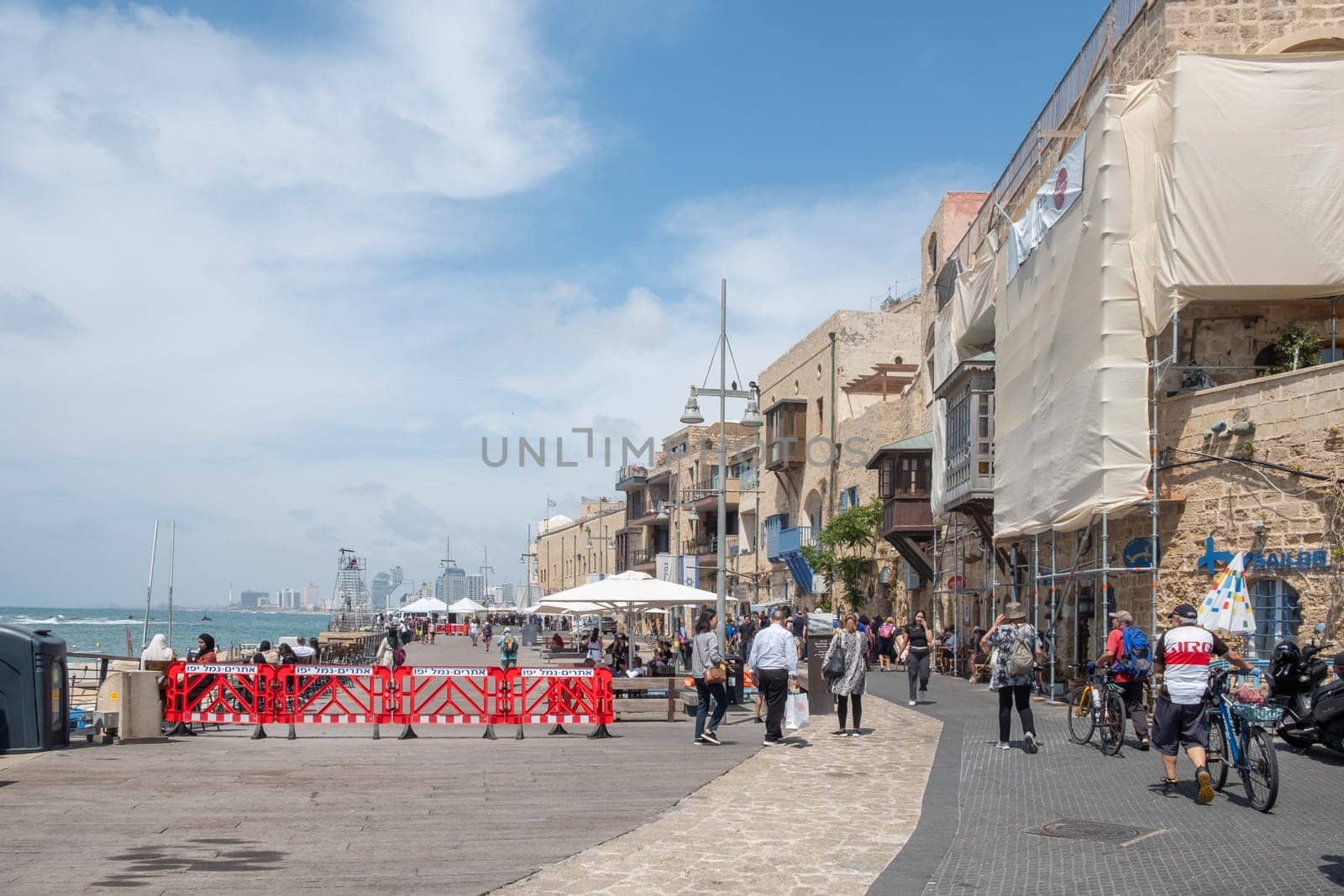 Tel Aviv, Israel - May 18, 2023: people enjoy walking at the beach  promenade of the beautiful old town of Tel Aviv.