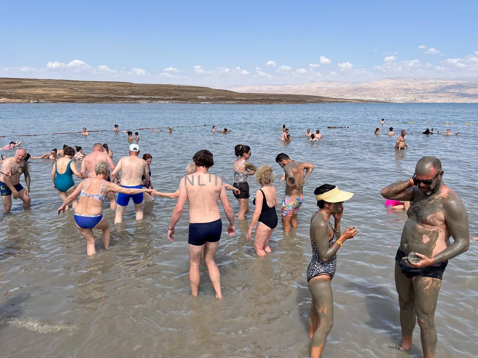 Dead Sea, Israel - May 20, 2023: people enjoy the bath in the saltern Dead Sea.Due to huge salt concentration in the sea, people swim without movement in the sea.