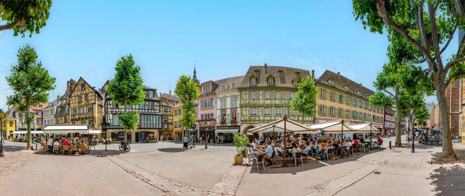 Colmar, France - June 21, 2023: Dominican square in Colmar, France with half timbered houses and tourists, enjoying sitting in the  cafes at a summer day.