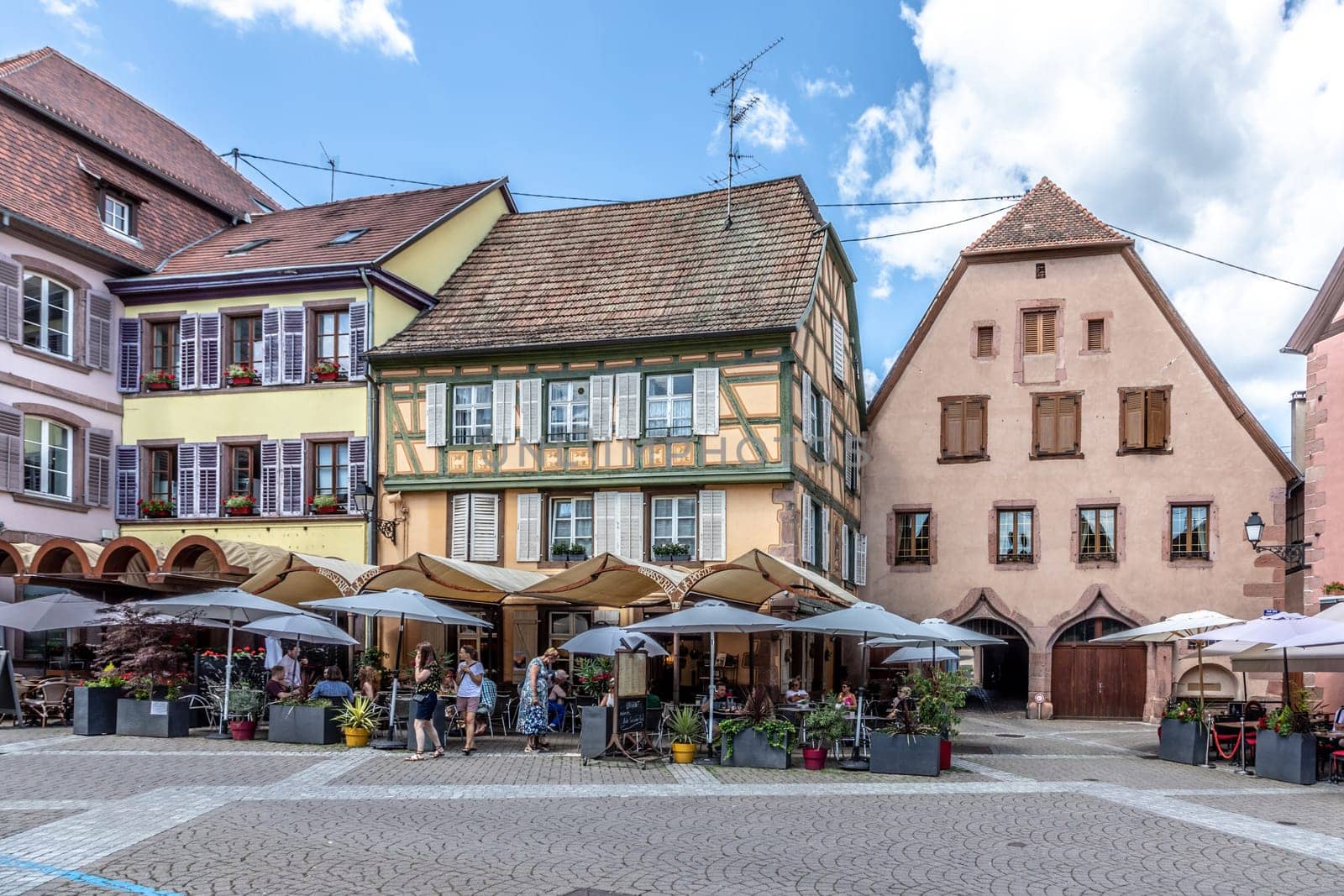 Ribeauville, France - June 23, 2023: A picturesque colorful street of half-timber buildings with shops and cafes in the village of Ribeauville, in the Alsace region.
