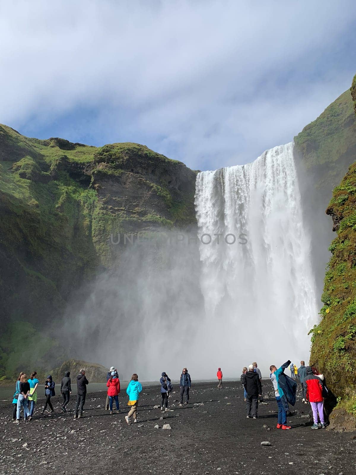 Skógafoss, Iceland -July 19, 2023: Tourists walking towards the Skógafoss waterfall in summer.