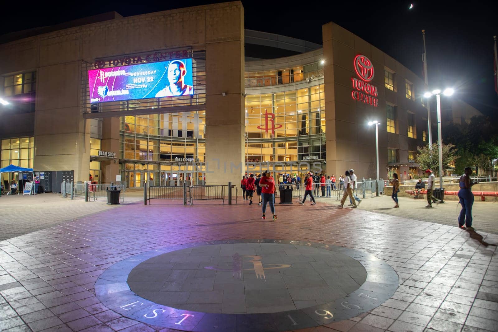 Houston, USA - October 20, 2023: nightview of downtown Toyota center in Houston. People hurry to entrance to join the Houston rockets basketball match.