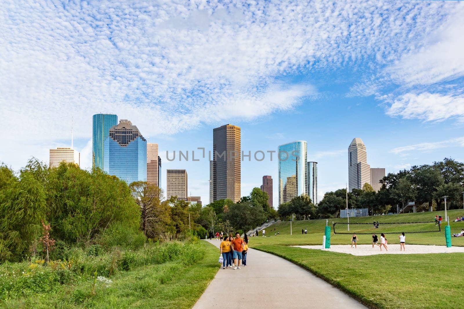 Houston, USA - October 22, 2023: people enjoy scenic view to skyline of Houston, Texas in morning light from Buffalo bayou park. Some play volleyball.