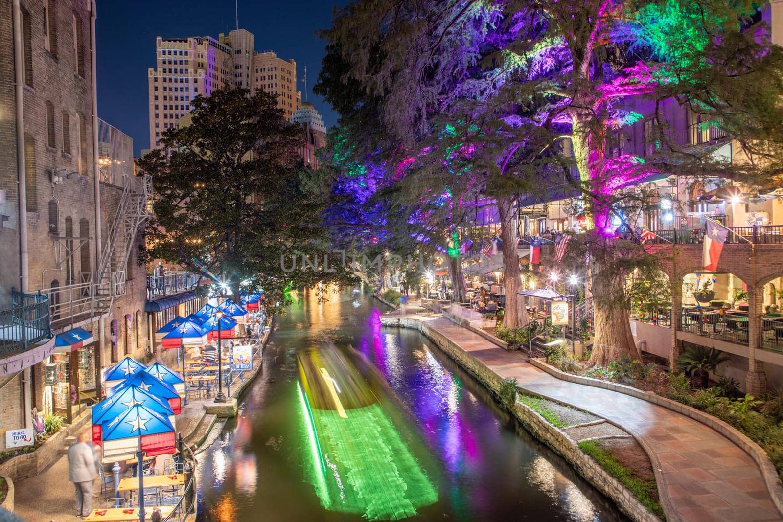 San Antonio, USA - October 31, 2023:  The San Antonio River Walk by night with illuminated trees and restaurants. City park and pedestrian street in San Antonio, Texas. USA
